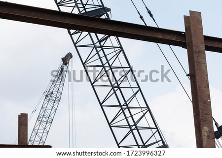 Consruction work with large steel structure and industrial cranes against a semi blue sky

