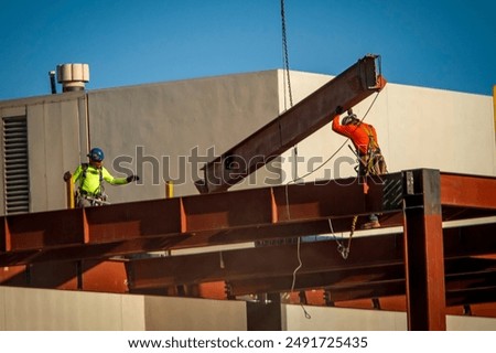 A consruction worker directing placement of a large steel beam that is atttached to a crane 