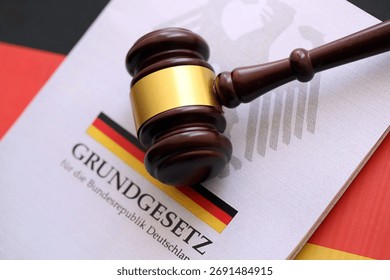 The constitution basic law book of Germany and judge hammer lies on Gremany flag background close up