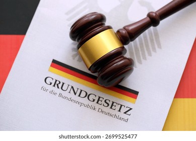 The constitution basic law book of Germany and judge hammer lies on Gremany flag background close up