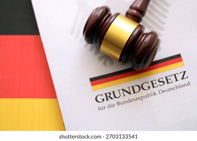 The constitution basic law book of Germany and judge hammer lies on Gremany flag background close up