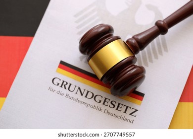 The constitution basic law book of Germany and judge hammer lies on Gremany flag background close up