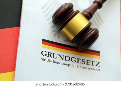 The constitution basic law book of Germany and judge hammer lies on Gremany flag background close up
