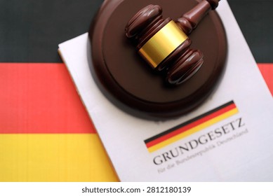 The constitution basic law book of Germany and judge hammer lies on Gremany flag background close up