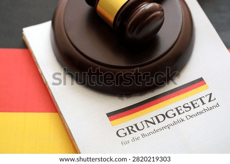 The constitution basic law book of Germany and judge hammer lies on Gremany flag background close up