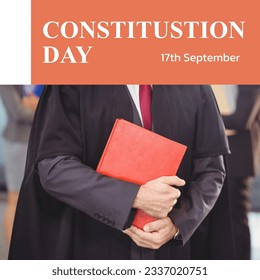 Constitution day text in white on orange and midsection of caucasian male attorney in gown with book. American constitution and federal government law celebration day digitally generated image. - Powered by Shutterstock