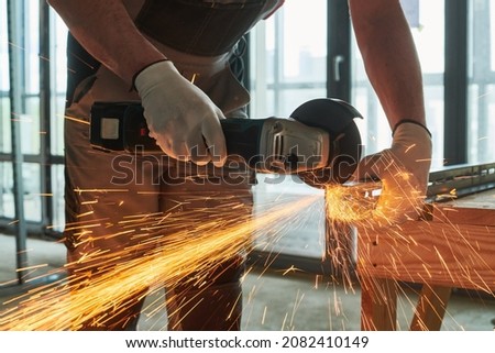 Constructiion work. Worker use angle grinder for metal cutting with sparks