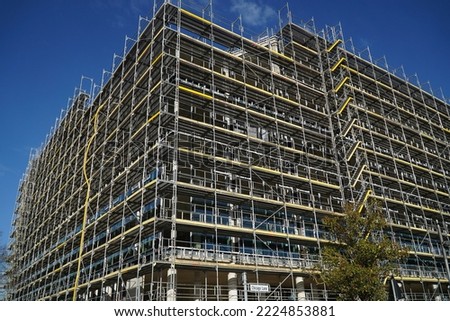 Construction activities and revitalization on former world exposition ground of Expo in 2000 in Hannover, Germany. Scaffolded new building project of a company in front of a bright blue sky.