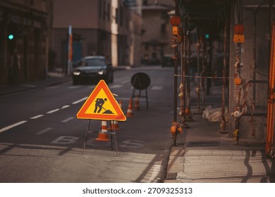 Construction activity stops traffic on busy city street during late afternoon light with urban scenery in the background