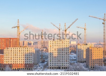 Construction of apartment buildings in new Moscow, cranes, skyscraper towers in winter.