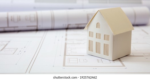 Construction blueprints concept. Residential building drawings and architectural house model on an office desk, copy space, template. Architect engineer workplace - Powered by Shutterstock