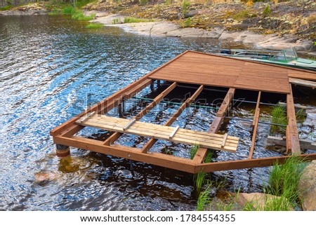 Construction of a boat dock. The future pier for boats and boats on the lake. Wooden flooring at the rocky shore. Infrastructure for water walks.