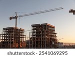 Construction boom in western Ukraine. A construction crane silhouetted against the warm glow of an early morning sky.