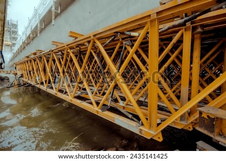 Construction of a bridge over the Kamienna River in Ostrowiec.Complex structure of steel, construction scaffolding, on a bridge construction site under a foggy grayish rainy sky.