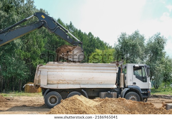construction bucket loading a truck with sand at a\
construction site