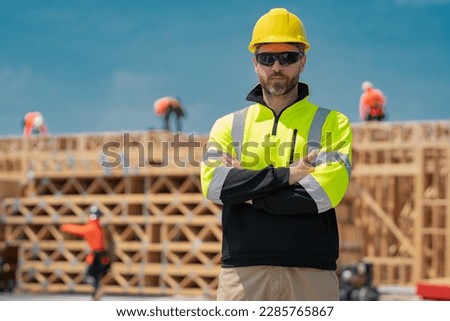 Construction builder in building uniform on buildings construction background. Builder at the construction site. Man worker with helmet on construction site. Bilder in hardhat.