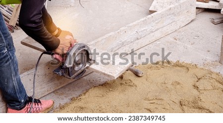 Construction builder worker uses a circular saw to cut wood at building site for preparation to build concrete floor on the work area.