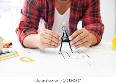 Construction and building concept. Engineers using a Drawing Compass with drawings in construction on blueprints in office.