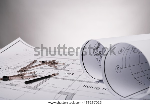Construction of\
the building layout, building drawing on paper, a set of drawing\
tools, blueprints rolled up into a\
roll.
