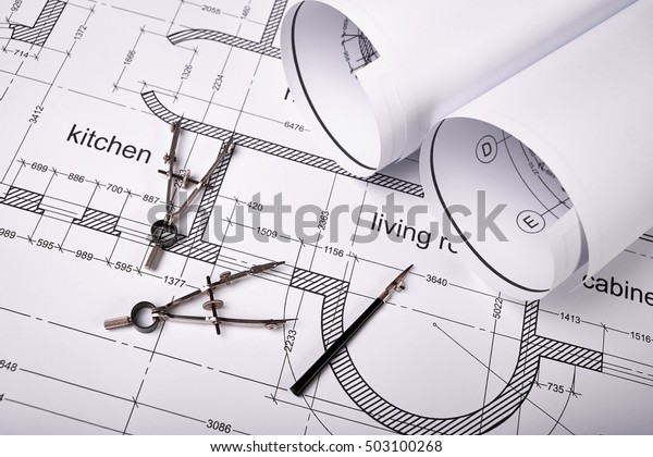Construction of\
the building layout, building drawing on paper, a set of drawing\
tools, blueprints rolled up into a\
roll