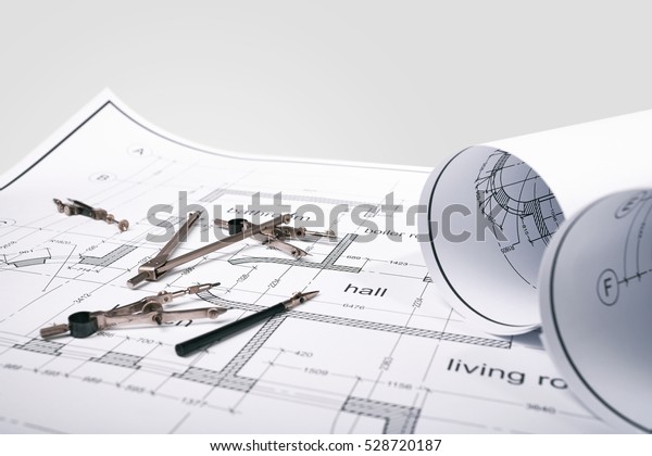 Construction of\
the building layout, building drawing on paper, a set of drawing\
tools, blueprints rolled up into a\
roll