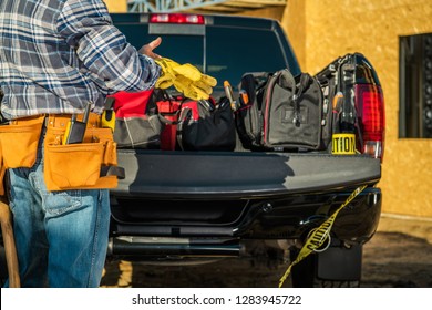 Construction Business Industry. Caucasian Contractor Worker Preparing Himself For the Job by Wearing Safety Gloves in Front of His Pickup Truck Full of Necessary Tools.