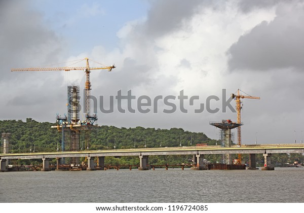 Construction of cable stayed bridge\
progressing from tall central concrete piers with the aid of tower\
cranes for the third bridge across Mandovi River in Goa,\
India