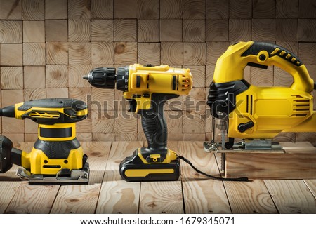 construction carpentry tools electric corded jigsaw cordless drill and wood sander on wooden background