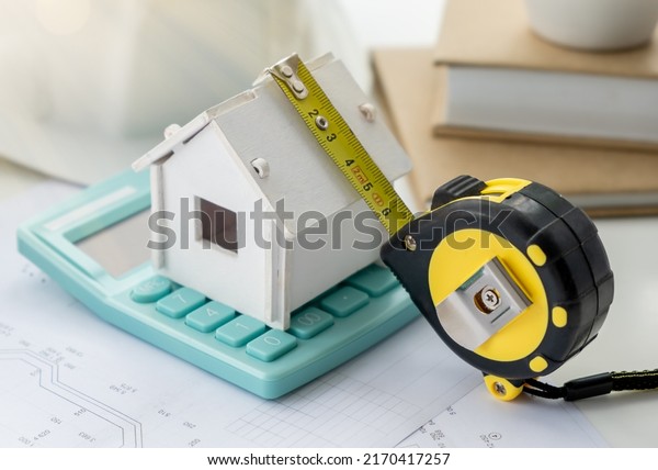 Construction company. Concept - construction\
business. Layout of the house. Helmet. Roulette lies on the\
drawings. Work in a construction company. Building. Engineer\'s\
desk. Layout plan of the\
rooms.