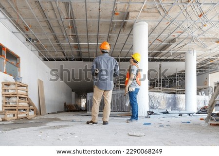 Construction concept of Engineer and Architect working with construction model and blueprint at construction site, Engineer and Architect discussing construction plan at building site