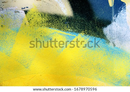 A construction container painted with bright spray paint to remove vandal marks. Blue, yellow, black, white colors on rough grunge surface, good for background with urban accents.