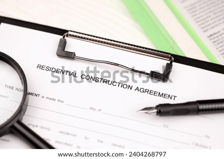 Construction contract form on A4 tablet lies on office table with pen and magnifying glass close up