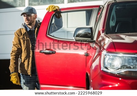 Construction Contractor Worker Wearing Eyes Protection Glasses and a Baseball Hat Staying Next to His Pickup Truck. Loading His Stuff and Going to Work.