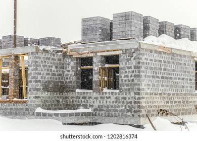 Construction of a country house stopped for the winter. Snow-covered suburban construction site. - Shutterstock ID 1202816374