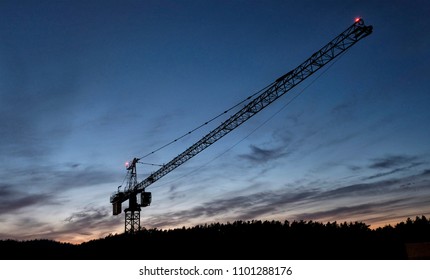 A construction crane against the background of the setting sun