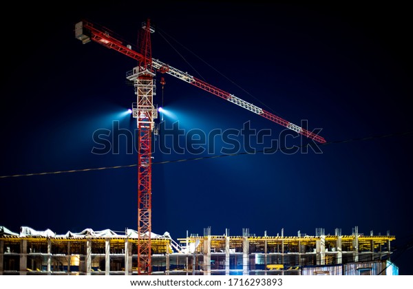 Construction crane, building site lighting at night,\
construction of an apartment building, beautiful night shot of the\
construction site