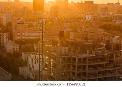 Construction crane and buildings under construction in urban city scape in back sunset light. Residential or business infrastructure development and expansion of the city. Selective focus, copy space