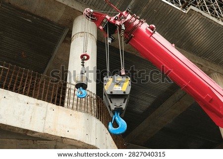 Construction Crane with Heavy Lifting Hooks. Large construction crane with heavy-duty lifting equipment rises above an active development site in Singapore. Editorial image documenting urban construction, engineering, infrastructure development, industrial equipment, and the continued growth of the modern city