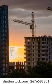 Construction crane operating at sunset, erecting a new apartment building, highlighting real estate development and urban growth within a vibrant cityscape