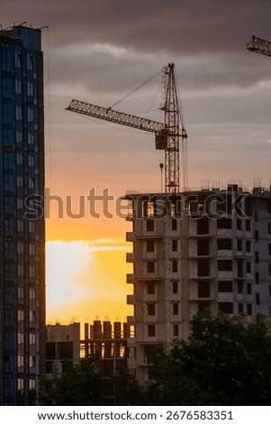 Construction crane operating at sunset, erecting a new apartment building, highlighting real estate development and urban growth within a vibrant cityscape