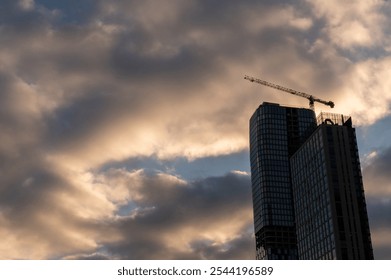 Construction cranes against dramatic sky. High rise building construction. Sunset or sunrise. - Powered by Shutterstock