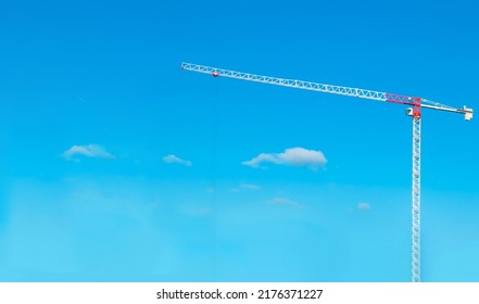 Construction cranes work on creation site against blue sky background. Bottom view of industrial crane. Concept of construction of apartment buildings and renovation of housing. Copy space. 