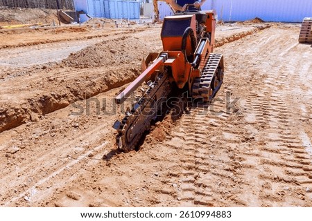 Construction crew utilizes trenching machine to create deep trench for utility lines at building site