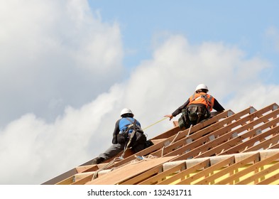 Construction Crew Working On The Roof Sheeting And Outriggers Or Ladder Of A New, Two Story, Commercial Apartment Building In Oregon