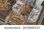 Construction crews work diligently on high-rise buildings in an urban area. Heavy machinery and materials are present, indicating the active development phase of new housing projects.