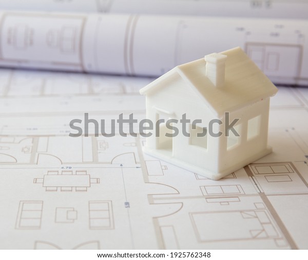 Construction design blueprints concept.\
Housing project drawings and architectural house model on an office\
desk. Architect engineer work\
space
