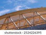 Construction detail of curved roof laminated timber beams or joists against a blue sky