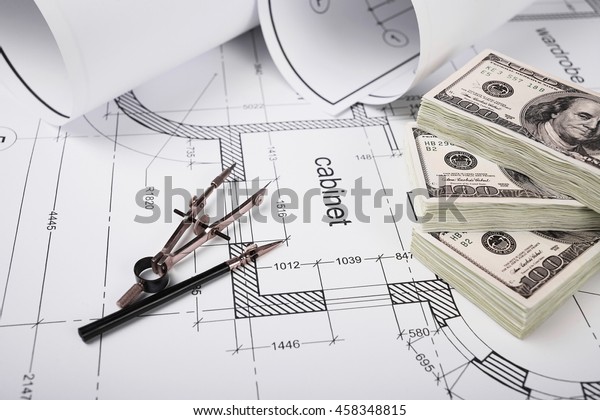 Construction drawings,\
drawing instruments, financing of the construction, packs of\
dollars, building drawing on paper, a set of drawing tools,\
blueprints rolled up into a\
roll.