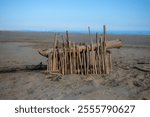 Construction of driftwood sticks placed on a sandy beach. Fine motor skills with hands, and fingers. Creativity and mindfulness in the natural environment. Copy space.