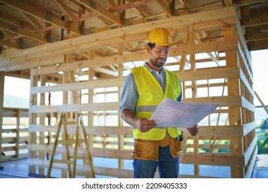 Construction Engineer Or Architect With Blueprints Visiting And Chechking Eco Building Site Of Wood Frame House.